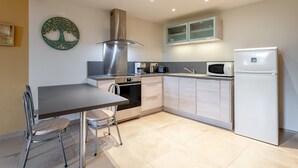 Eine moderne Küche mit Esstisch, Stühlen, Herd, Backofen, Mikrowelle und Kühlschrank.