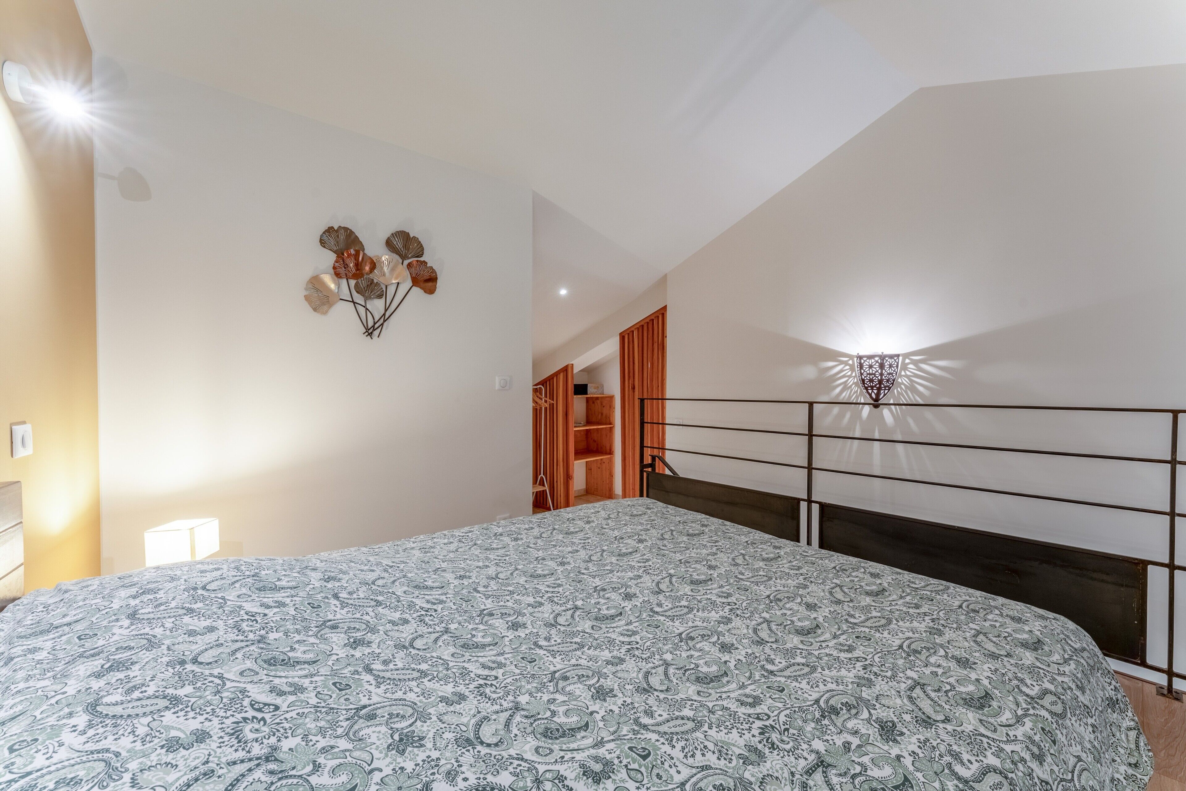 A bedroom with a bed, a wall-mounted light fixture, and a ceiling fan.