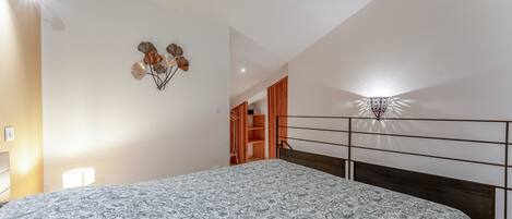 A bedroom with a bed, a wall-mounted light fixture, and a ceiling fan.