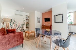 Ein modernes Wohnzimmer mit einem roten Sofa, einem Glastisch, einem Fernseher und einem Kamin.