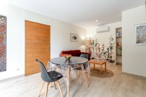 Ein modernes Wohnzimmer mit einem runden Glastisch, einem roten Sofa und einer Holztür.