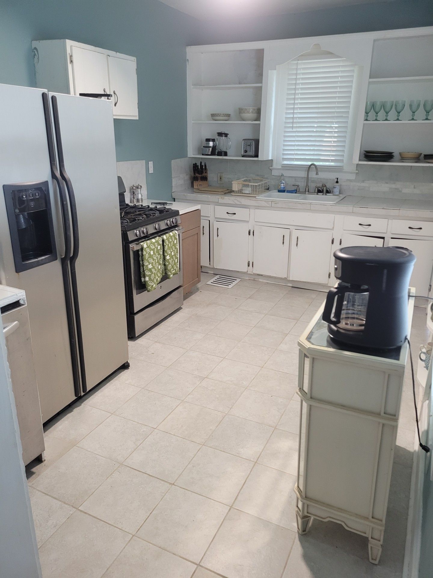 A kitchen with a refrigerator, stove, oven, and coffee maker.