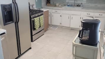 A kitchen with a refrigerator, stove, oven, and coffee maker.