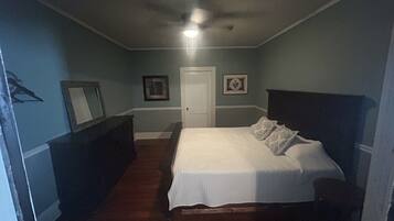 Une chambre à coucher avec un lit, une commode et deux tableaux encadrés accrochés au mur.