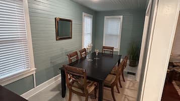 A dining room with a dark wooden table, six chairs, and a potted plant.