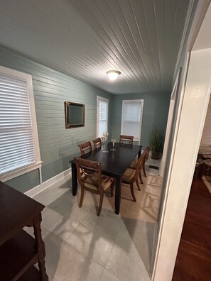 A dining room with a dark wooden table, six chairs, and a potted plant. - Southern Comfort (Tallahassee)