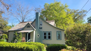 A two-story house with a gabled roof, a chimney, and a front porch.