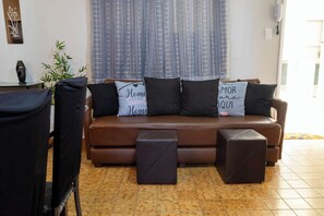 Ein Wohnzimmer mit einem braunen Sofa, zwei schwarzen Kissen und einem kleinen Tisch.