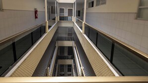 Käytävällä on keskellä kulkuväylä, lasikaiteet, laatoitetut seinät ja vasemmalla puolella palosammutin.