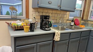 Ett kök med gråa skåp, en kaffebryggare och diverse köksredskap på bänkskivan.