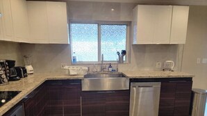 A modern kitchen with dark wood cabinets, a stainless steel sink, and a dishwasher. - Modern Ceramic Retreat - Newly Remodeled 2BR/2BA (North Miami Beach)