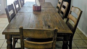 Ein Esszimmer mit einem großen Holztisch, sechs Stühlen, einer kleinen Vitrine und einer Deckenleuchte.