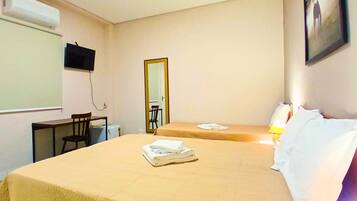 Habitación de hotel con dos camas, un escritorio, una silla, un televisor y un espejo.