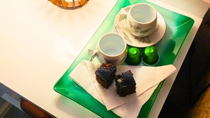 A tray with two cups, two green bottles, and two pieces of cake on a white table.