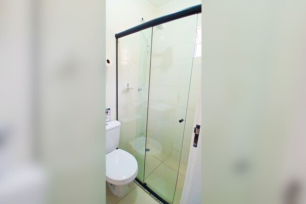 A bathroom with a glass shower enclosure, a toilet, and a sink. - Pousada Guanabara Inn Campinas-SP (Campinas)