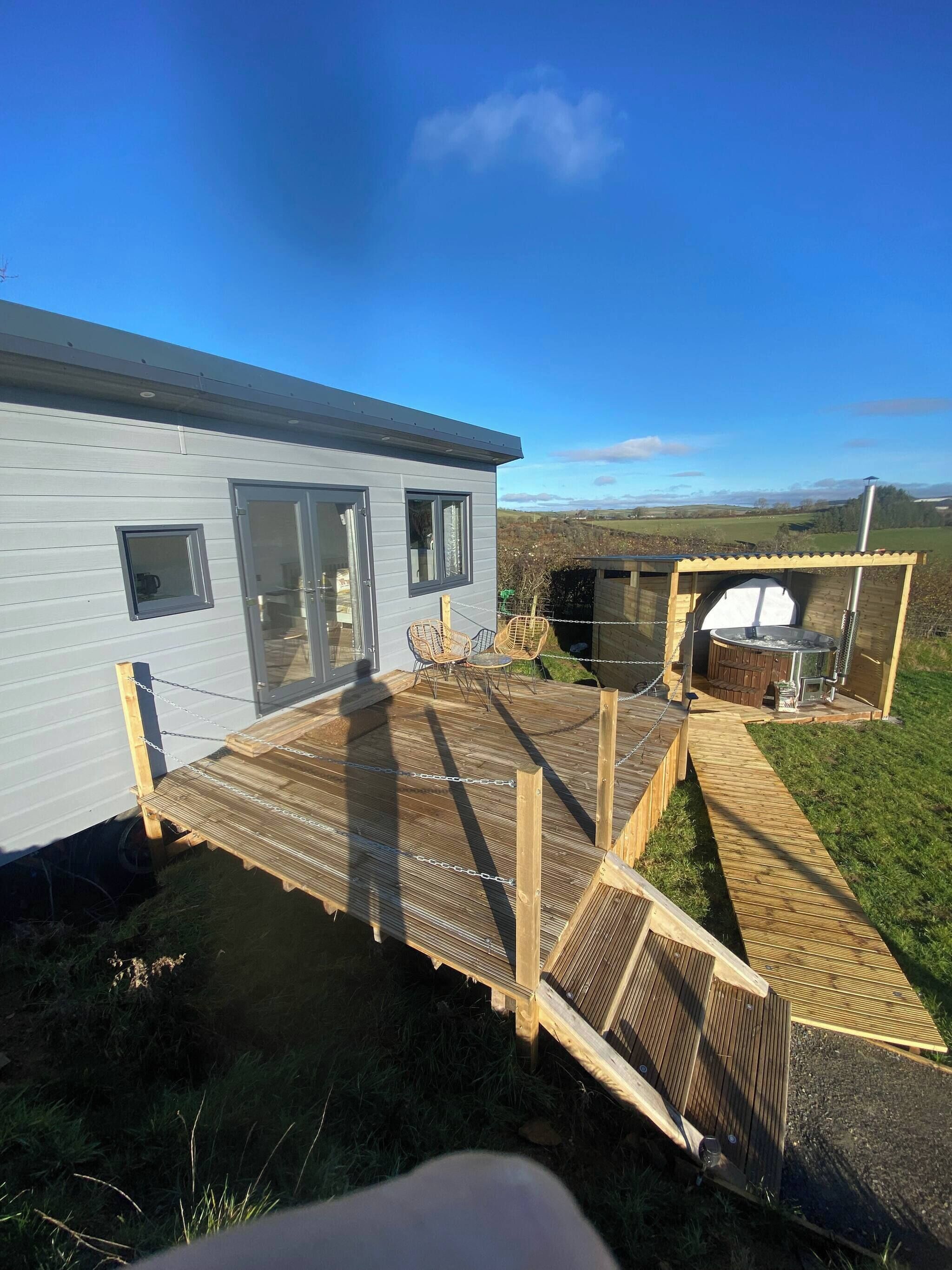 A modern house with a deck, a barbecue area, and a scenic view.