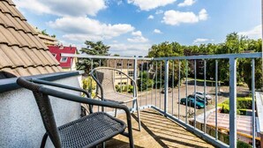 Un balcon donnant sur un parking et des immeubles.