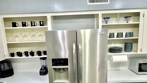 A stainless steel refrigerator with a water dispenser, a microwave, and a coffee maker on the counter. - Midcity Sunrise (Lake Charles)