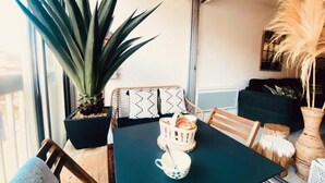 A dining area with a table, chairs, a potted plant, and a basket with bread. - Apartment in Grau du Roi by the Beach (Le Grau-Du-Roi)