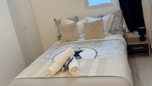 Un lit bien fait, avec une couvre-lit à motifs, une serviette enroulée et un coussin décoratif.