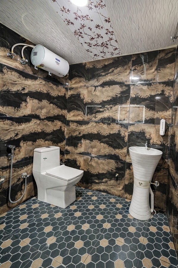 A bathroom with a toilet, sink, and shower. The walls have a unique patterned design, and the floor has a hexagonal tile pattern. - Hotel Rism Suites Koramangala (Bengaluru)