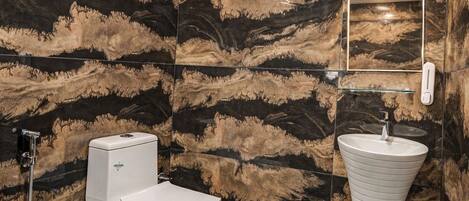 A bathroom with a toilet, sink, and shower. The walls have a marbled pattern, and the floor has a hexagonal tile pattern.