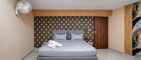 A modern bedroom with a large bed, a wall-mounted fan, and a patterned wallpaper.