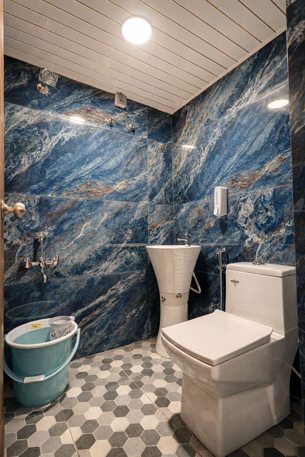 A bathroom with a marble backsplash, a toilet, a sink, and a shower.
