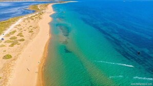 Vista aérea de una zona costera con playa arenosa y aguas azul turquesa.