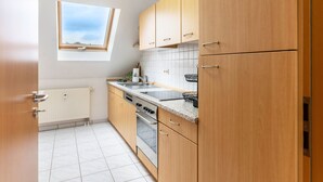 Une cuisine avec des meubles de rangement en bois, une fenêtre, un évier et une cuisinière.