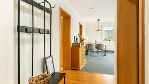 Un couloir avec un porte-manteau, une armoire en bois et un coin repas comprenant des chaises et une table.