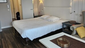 Ein modernes Hotelzimmer mit einem großen Bett, Nachttischen, einer Couch und einem kleinen Tisch mit einem Korb.