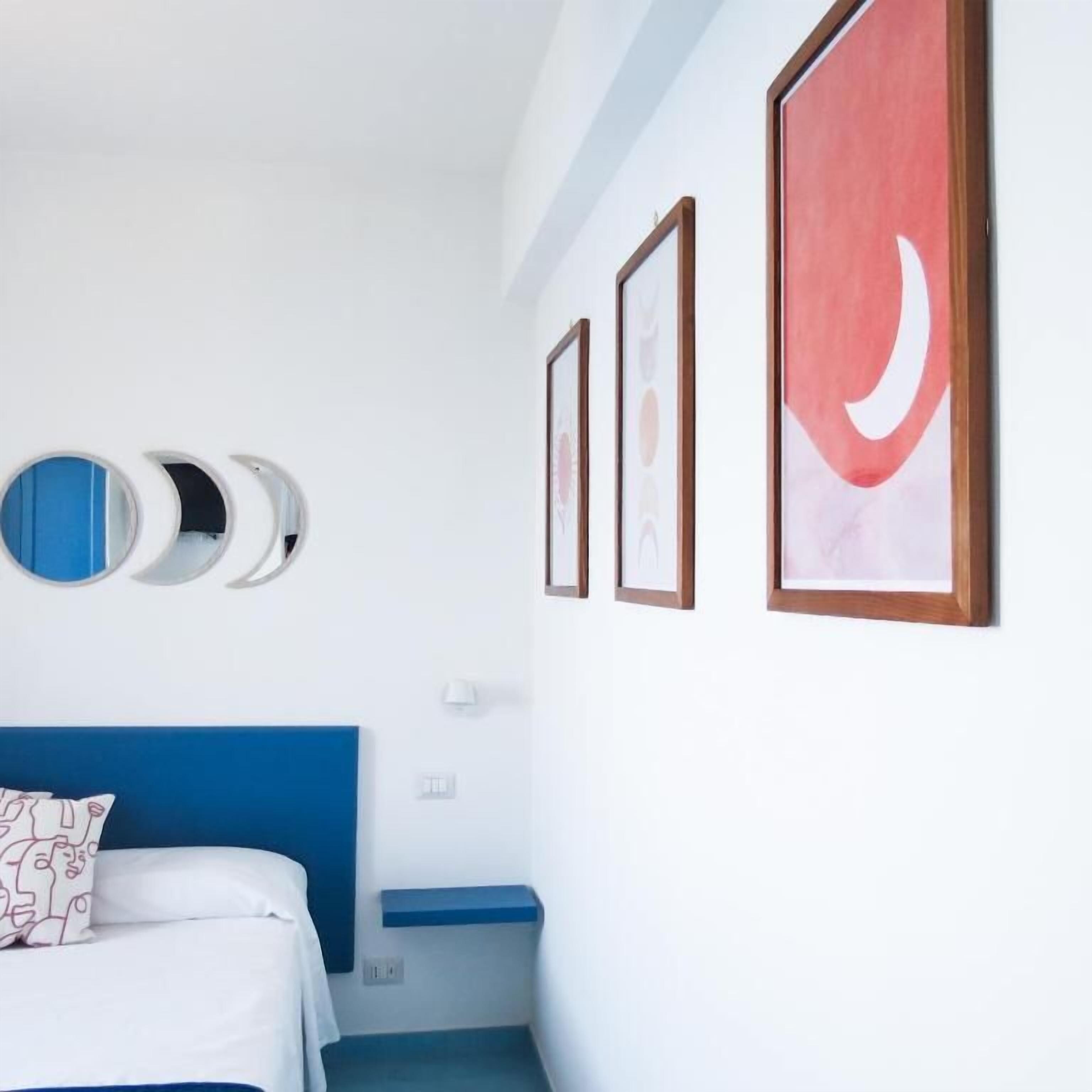 A hotel room with a bed, a nightstand, and three framed pictures on the wall.