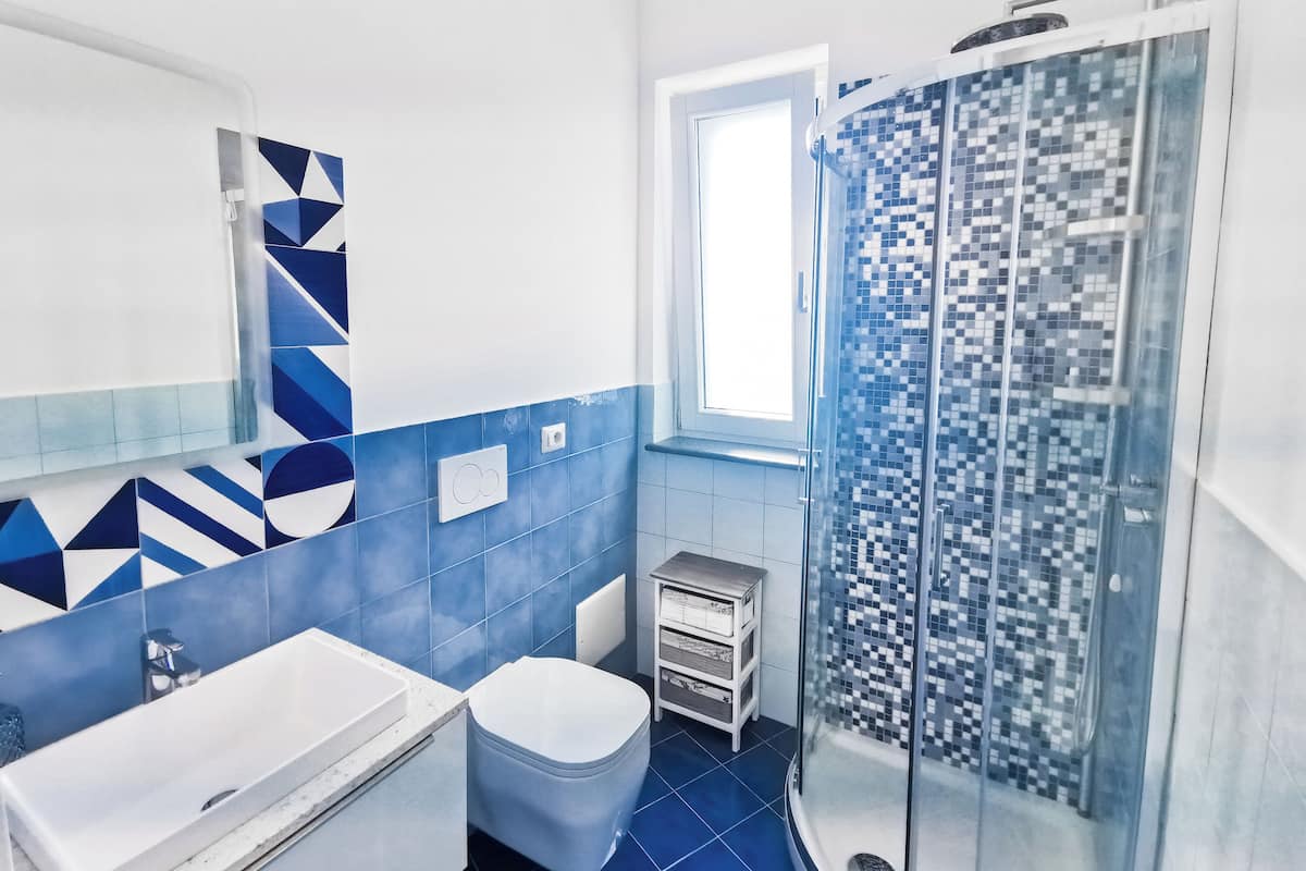 Egy modern fürőszoba zuhanyzóval, WC-vel és mosdókagylóval.