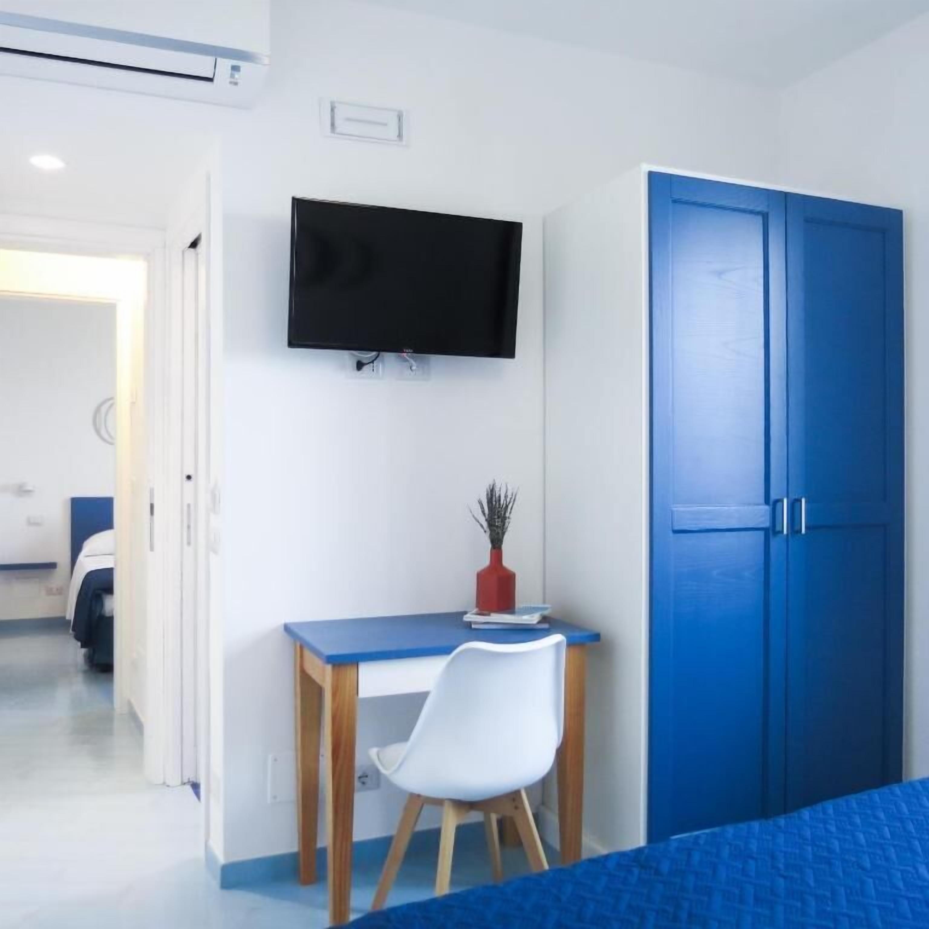 A bedroom with a bed, a desk, a chair, a television, and a wardrobe.