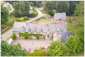 A stone building with multiple gabled roofs, a central courtyard, and surrounding greenery. - 1930s-style house, large garden, 10-minute walk to beach. Ideal for 2 to 3 families. (Erquy)