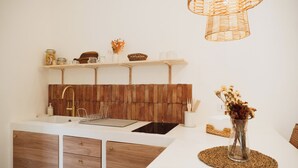 Cozinha moderna com painel de madeira, armários brancos e luminária pendente.
