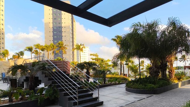 A modern outdoor area with a staircase leading to an upper level, surrounded by palm trees and greenery.