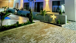 A modern multi-story hotel with a well-lit entrance and a paved courtyard. - 2-bedroom apartment in Kigali with AC, a swimming pool, and great city views. (Kigali)