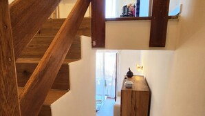 Una escalera de madera que lleva a una plataforma con una mesita y un florero.