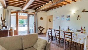 Un coin repas avec une table dressée pour quatre personnes, des chaises en bois et un plafond rustique.