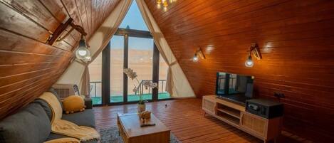 Un acogedor loft con interior de madera, un ventanal con vistas, un sofá, una mesa de centro y un televisor.