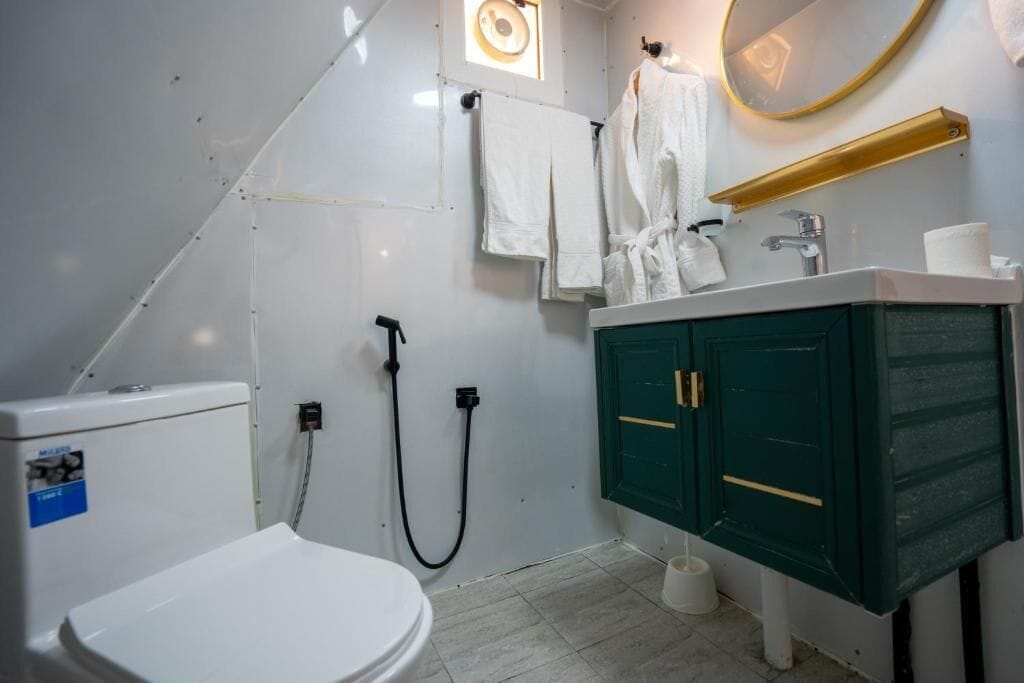A bathroom with a toilet, a shower, a sink, and a mirror.