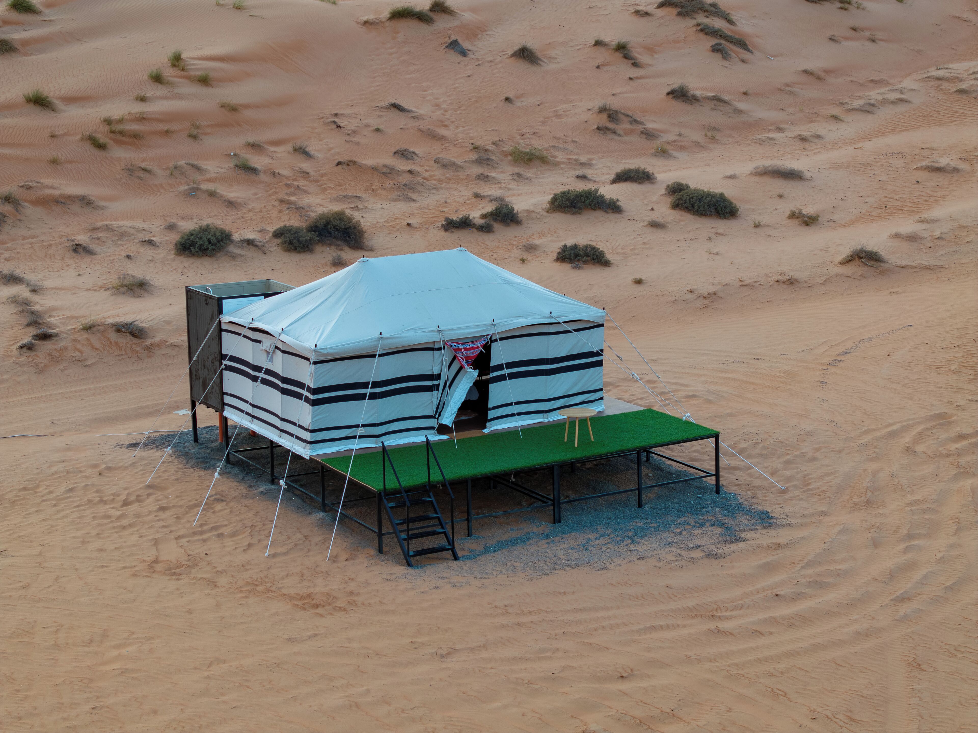 A tent with a striped design, a small table, and a ladder.