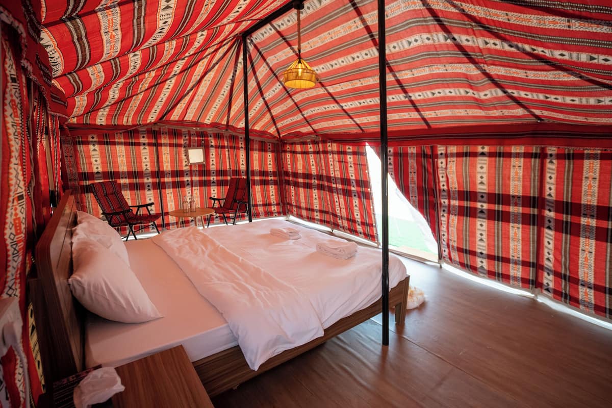 A cozy, patterned tent-style room with a bed, a table, and a chair.