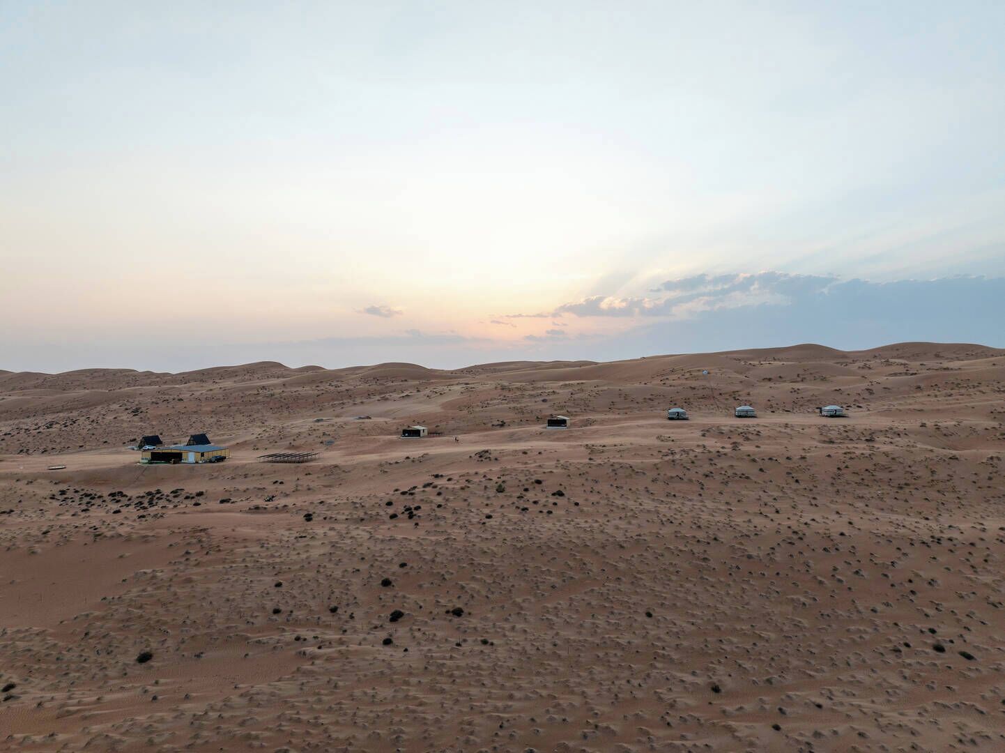 A desert landscape with several small, isolated structures, likely accommodations, spread across the terrain.