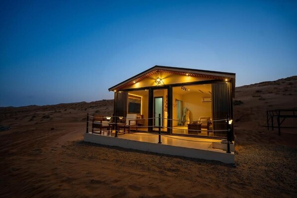 A desert-style building with a glass facade, outdoor seating, and a star-shaped light fixture.
