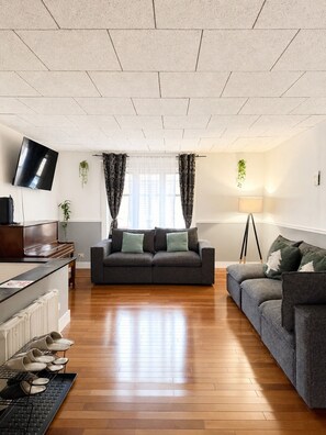 A living room with a sofa, a TV, a lamp, and a piano.