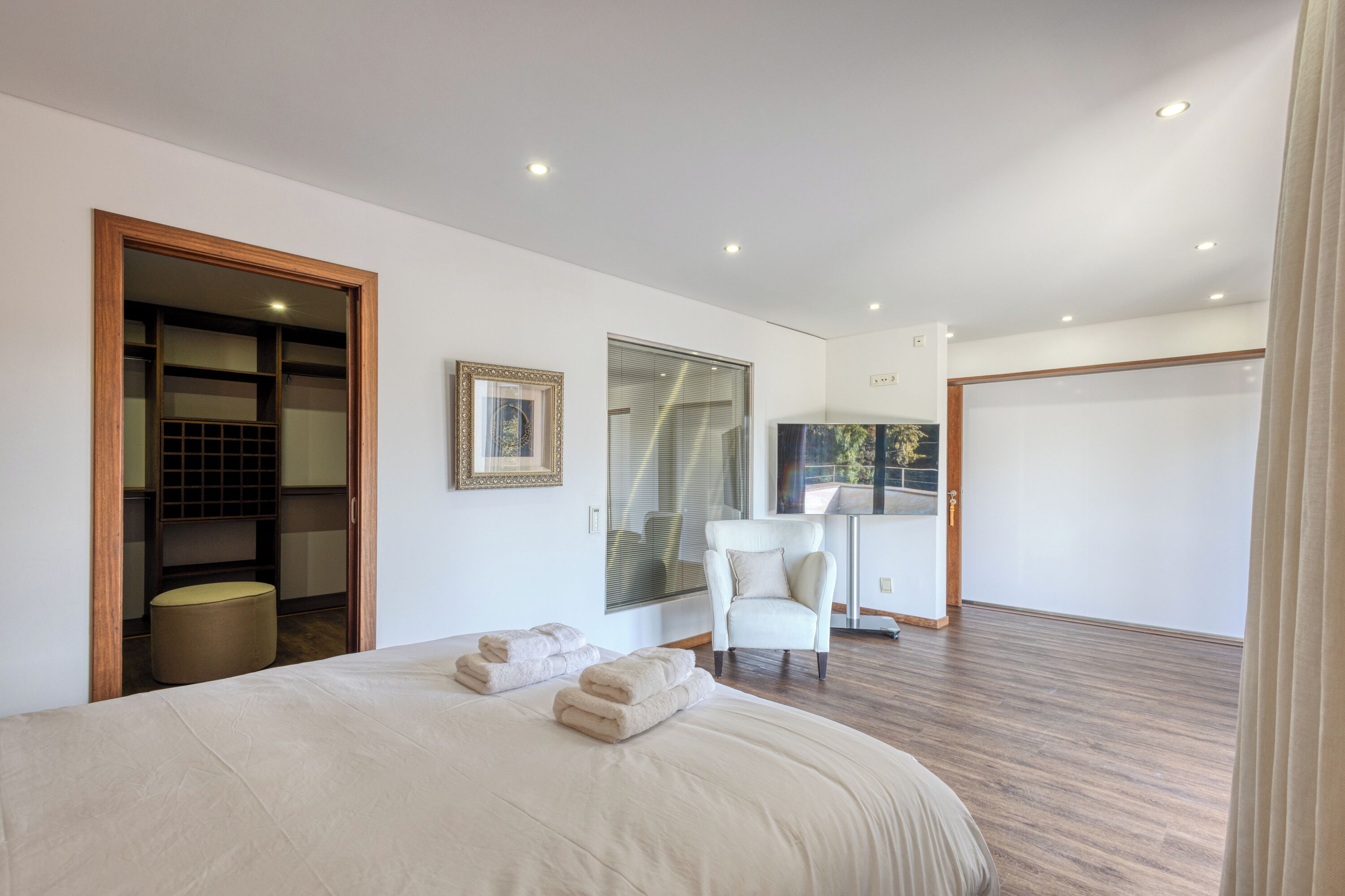A modern bedroom with a large bed, a chair, and a desk.
