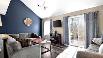 A living room with a sofa, a coffee table, a flat-screen TV, and a fireplace.